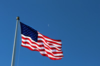 An American Flag Isolated on Blue Sky with Quarter Moon Peeking